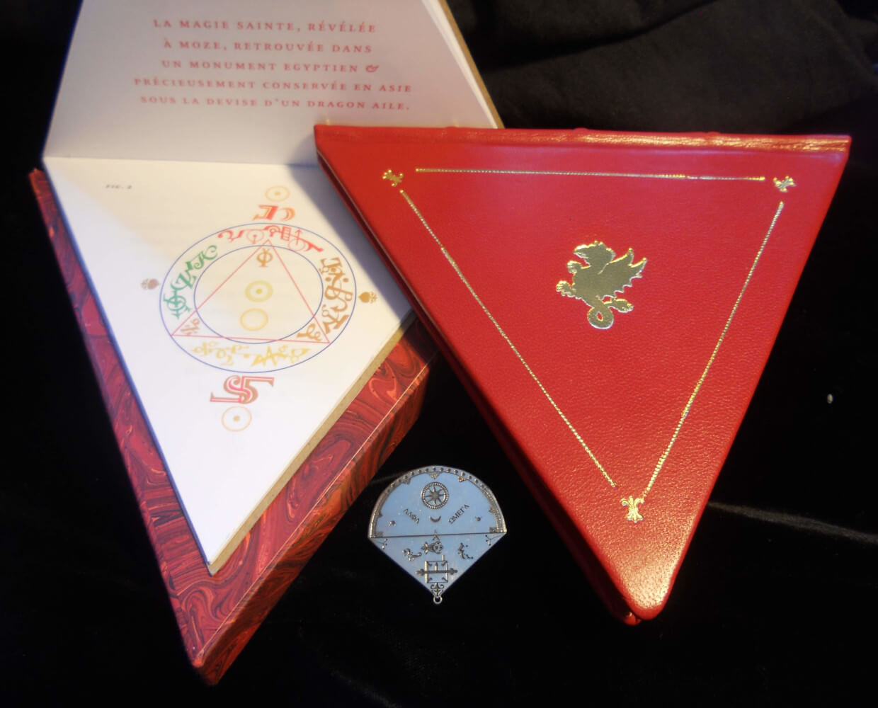 Facsimile red leather Triangular Book of Saint-Germain with ritual diagram and silver talisman for longevity, treasure, and invocation.